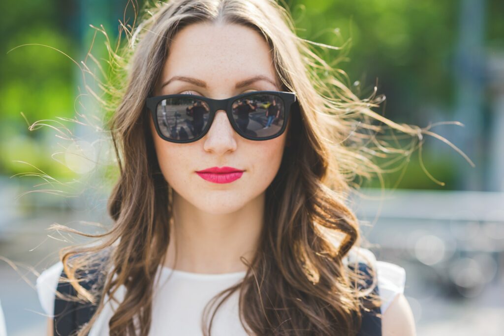 Portrait of a young beautiful millennial woman looking in camera wearing sunglasses