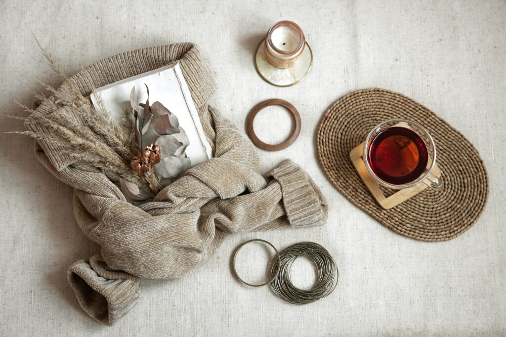 Still life with women bracelets, a cup of tea and dried flowers on a warm sweater