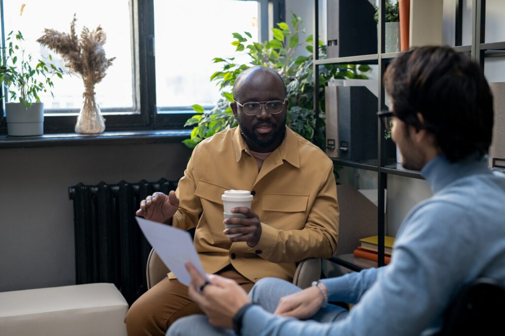Young African-American man consulting his colleague with paper