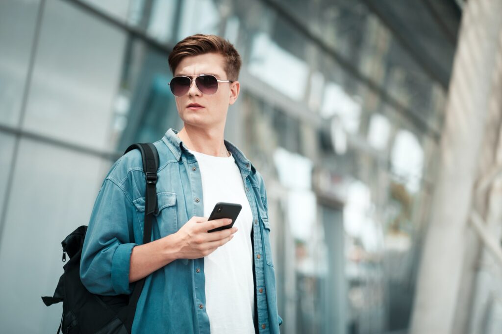 Young man in sunglasses with a smartphone in his hands